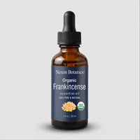 A 1 fl oz amber glass dropper bottle of Nexxon Botanics Organic Frankincense essential oil, featuring a dark navy blue label with white text and a black dropper cap, set against a light gray background.