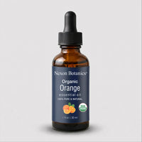 A 1 fl oz amber glass dropper bottle of Nexon Botanics Organic Orange essential oil, featuring a dark blue label with white text and an orange graphic, set against a light gray background.