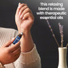 Woman applying Zen Sleep essential oil roll-on to her wrist with lavender flowers in the background.